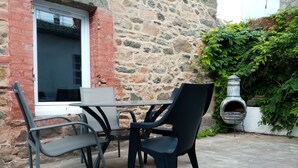 Zona esterna con sedute, un muro in pietra, una finestra in mattoni e un forno a pizza.