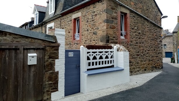 Una casa in pietra con un recinto di legno, una porta blu e un piccolo balcone.
