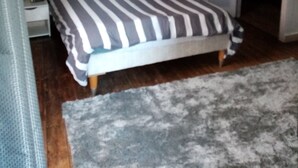 Una camera da letto con un letto, un comodino, una porta e un tappeto.