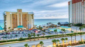 A hotel with multiple floors, a parking lot, and a view of the ocean.