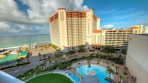 A hotel with multiple high-rise buildings, a swimming pool, and a beach view.