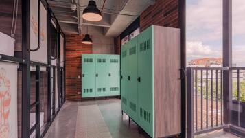 A corridor with lockers, a brick wall, and a window overlooking buildings.