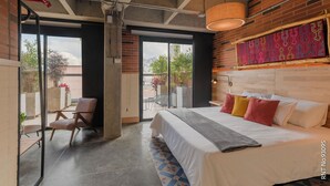 Een moderne hotelkamer met een groot bed, een stoel en uitzicht op het omliggende landschap.