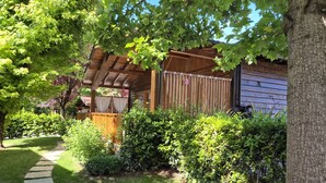 Eine Holz-Pergola mit überdachter Sitzgruppe, einem Kiesweg und üppigem Grün.