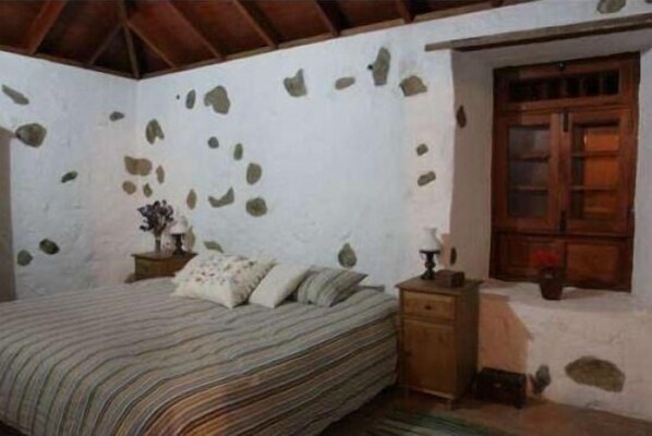 A bedroom with a bed, a nightstand, and a wooden wardrobe.