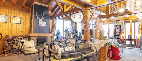 Un interior acogedor de cabaña de troncos con chimenea, paredes de madera y un árbol de Navidad decorado.