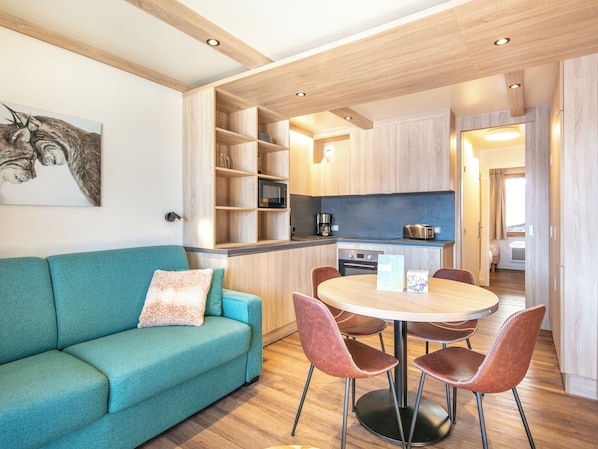 A compact living space with a sofa, dining table, chairs, kitchen area, and a small sleeping area. - Residence La Duit - Vacanceole (La Léchère)