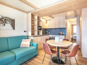 A compact living space with a sofa, dining table, chairs, kitchen area, and a small sleeping area. - Residence La Duit - Vacanceole (La Léchère)