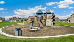 Een speelplaats met een glijbaan, klimconstructies en picknicktafels.