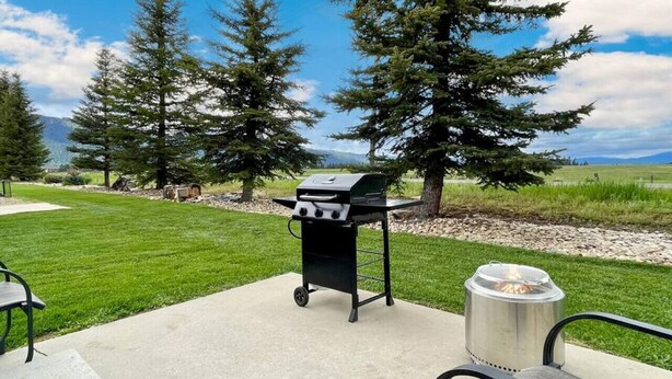 Een terras buiten met een barbecue, een vuurkorf en een zitgedeelte.