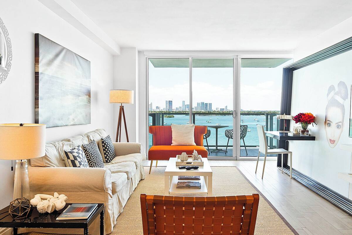 A modern living room with a sofa, coffee table, and a view of the city and water.