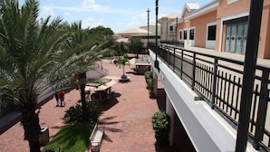 A courtyard with palm trees, a bench, and a building with a sign that reads "Maggiano's". - 110 Regal Palms (Davenport)