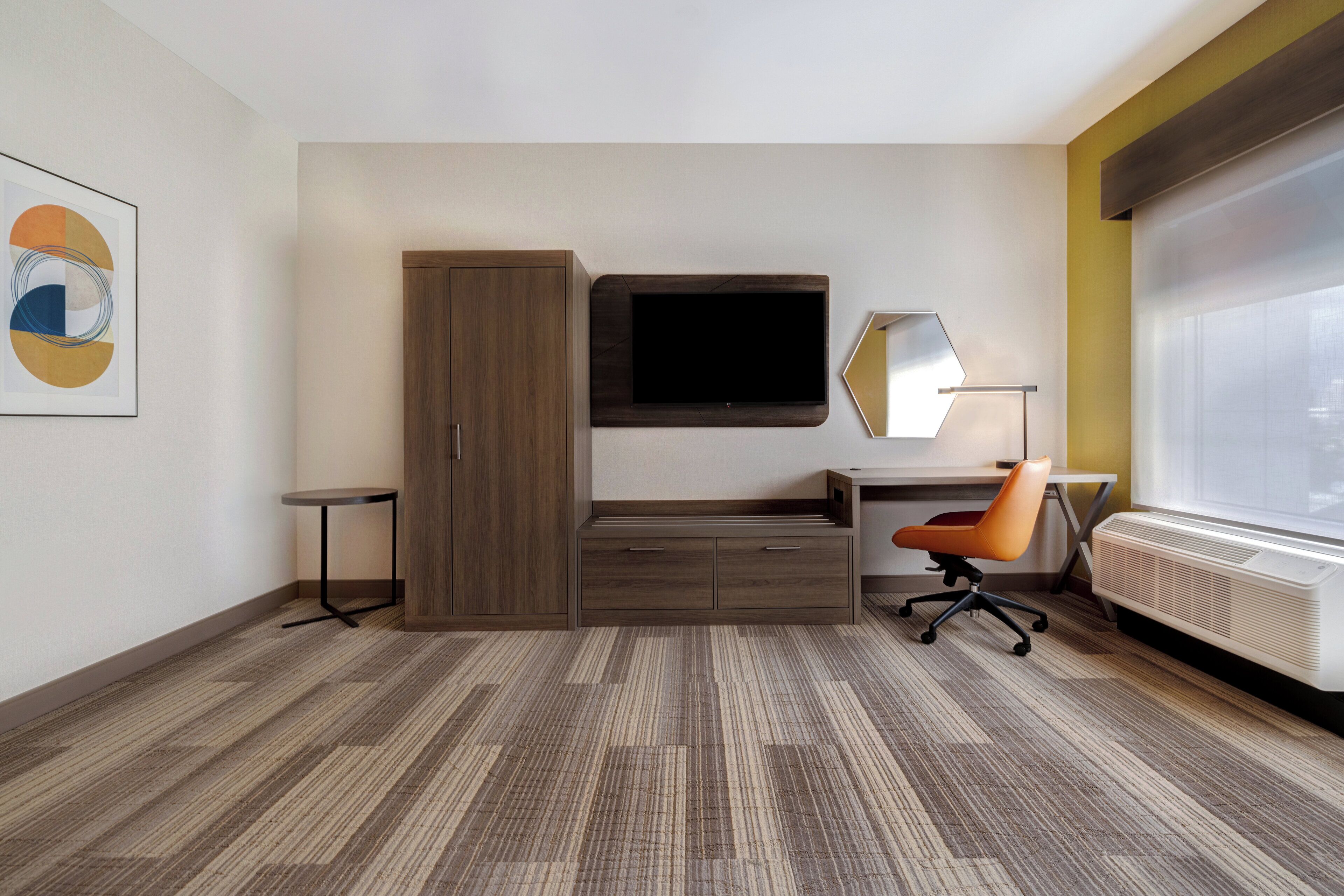 Una habitación de hotel moderna con una cama grande, un escritorio con silla, un televisor de pantalla plana, un espejo y un radiador.