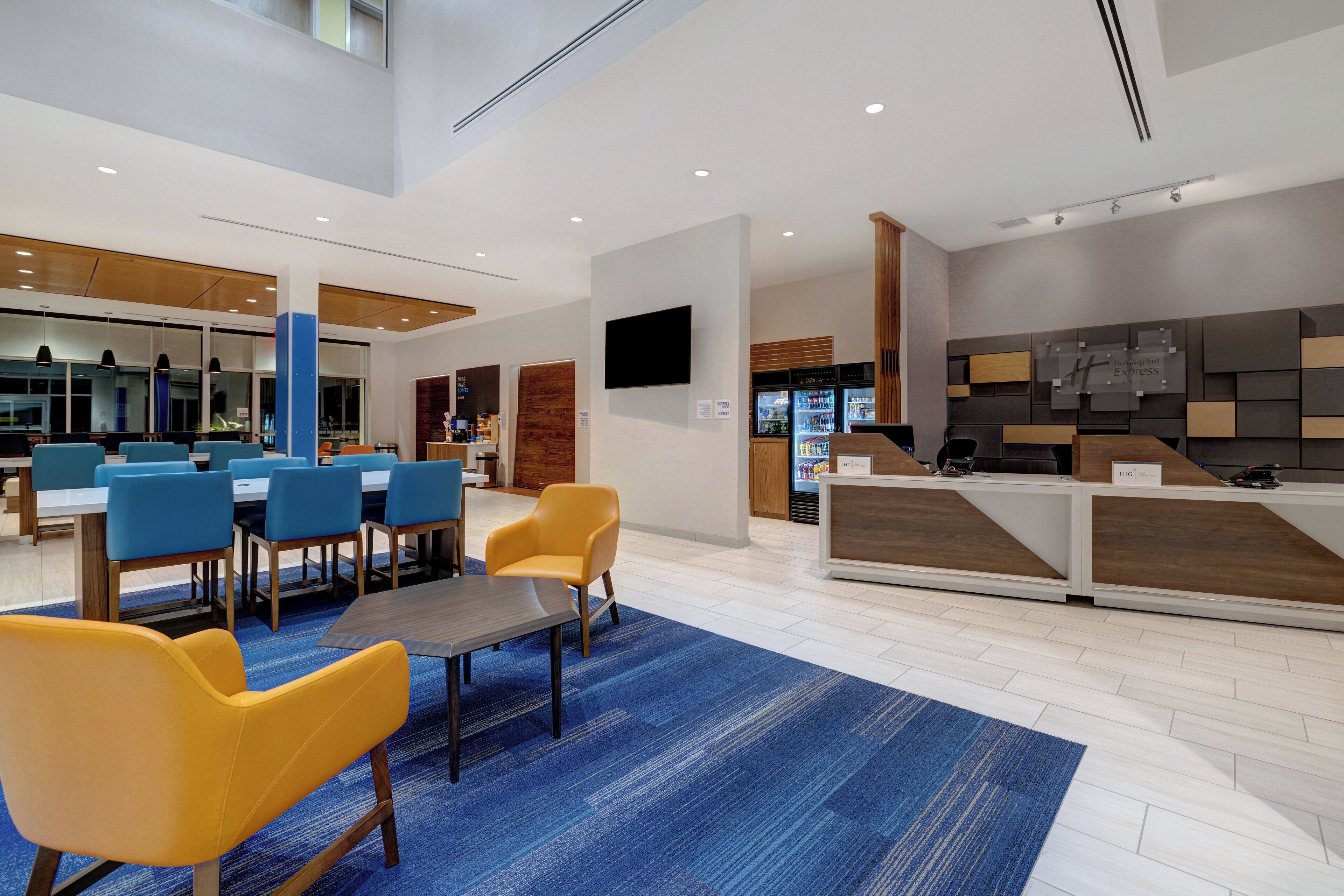 Un hall d’hôtel comprenant un comptoir d’accueil, un espace salon avec des fauteuils et un appareil à café.