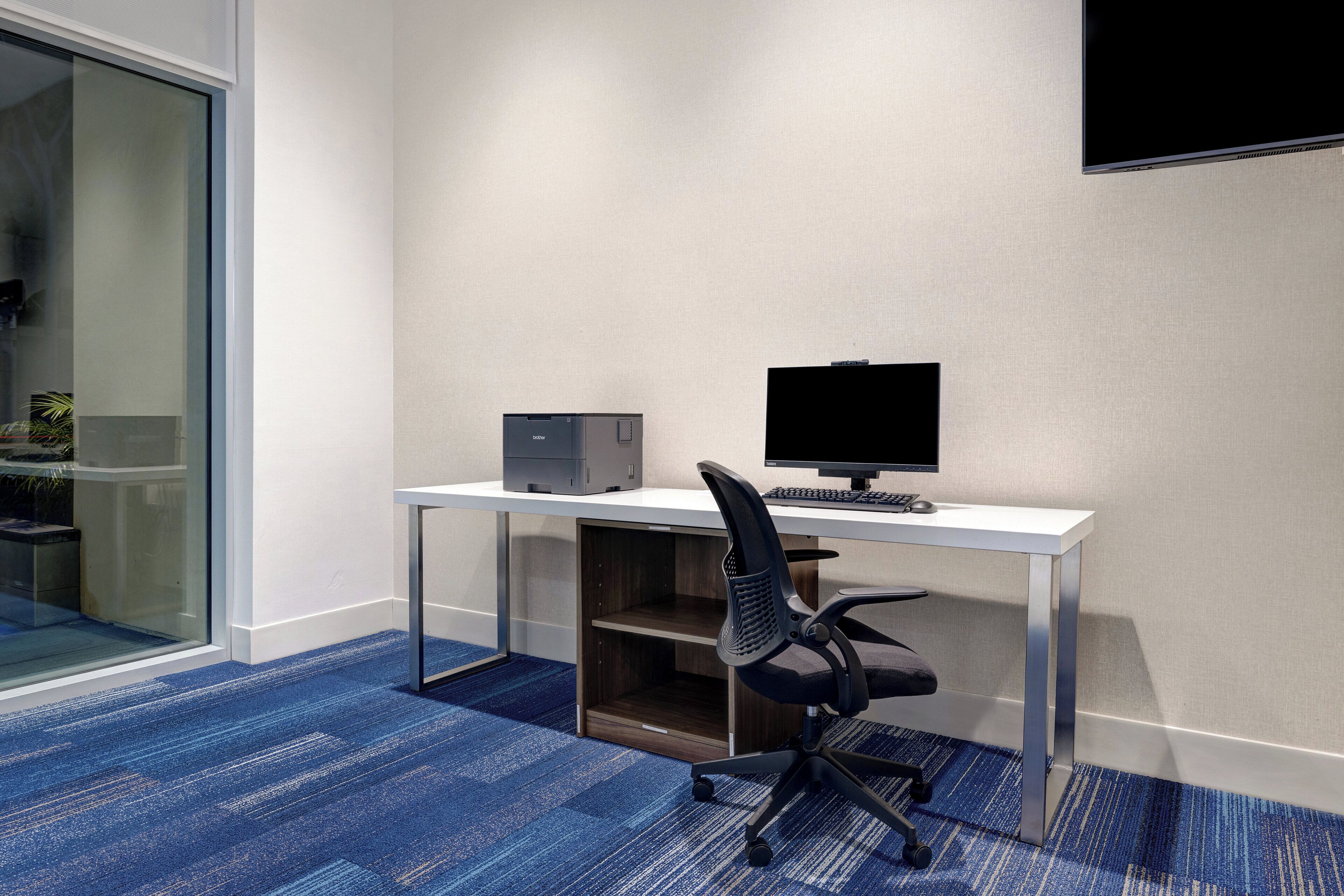 Un espacio de oficina moderno con un escritorio, computadora y silla.