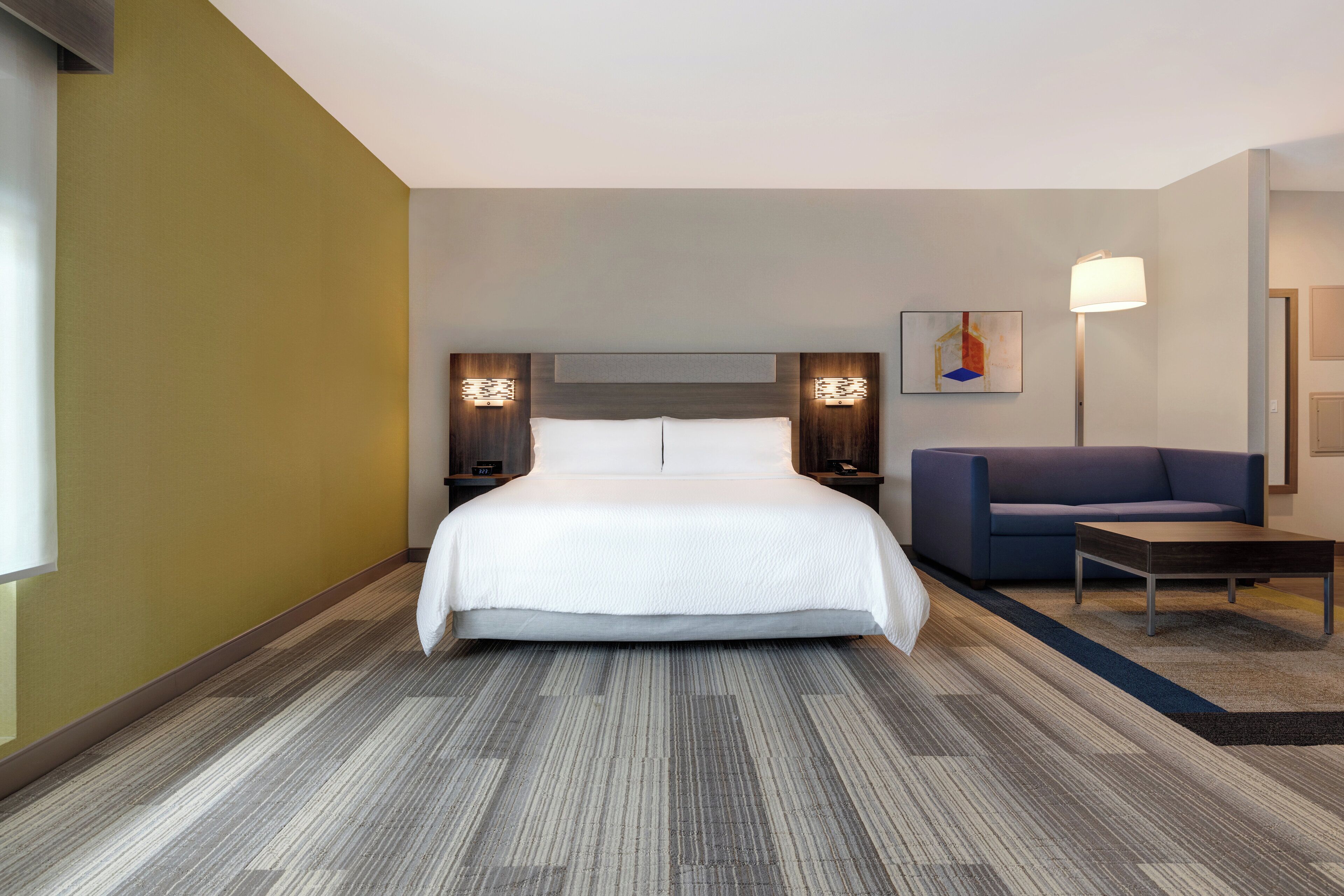 Ein Hotelzimmer mit einem großen Bett, einer Couch, einem Schreibtisch und zwei Wandlampen.