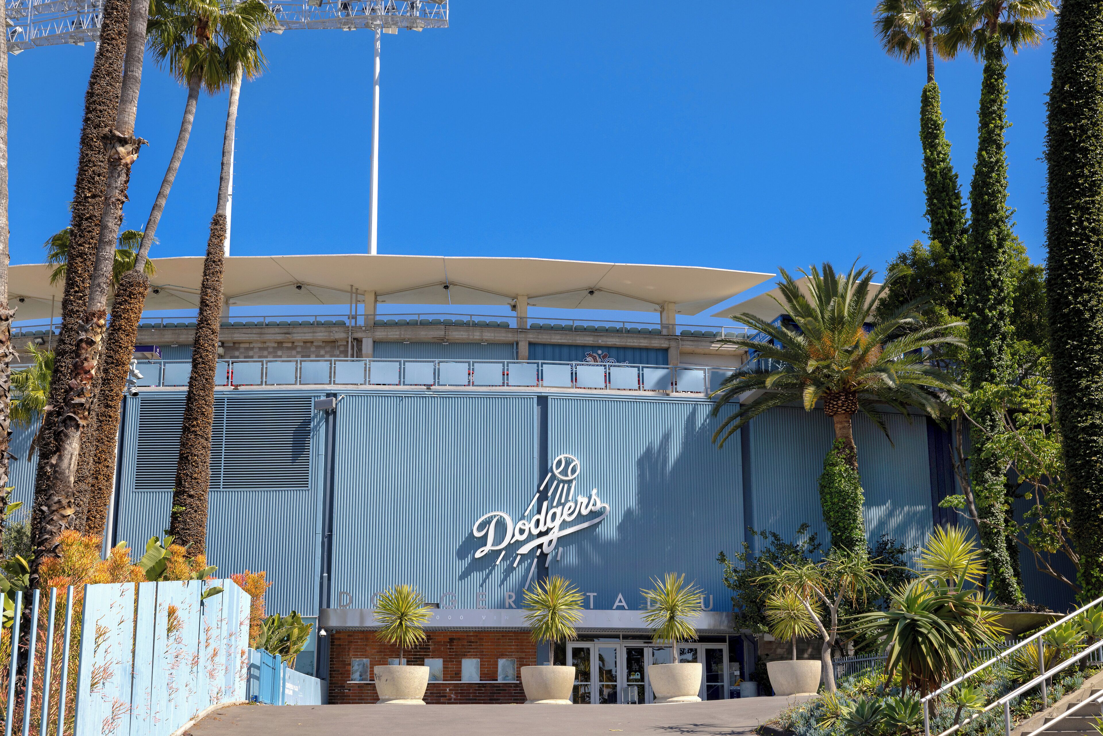A stadium with a prominent 'Dodgers' sign, surrounded by palm trees and a covered walkway.