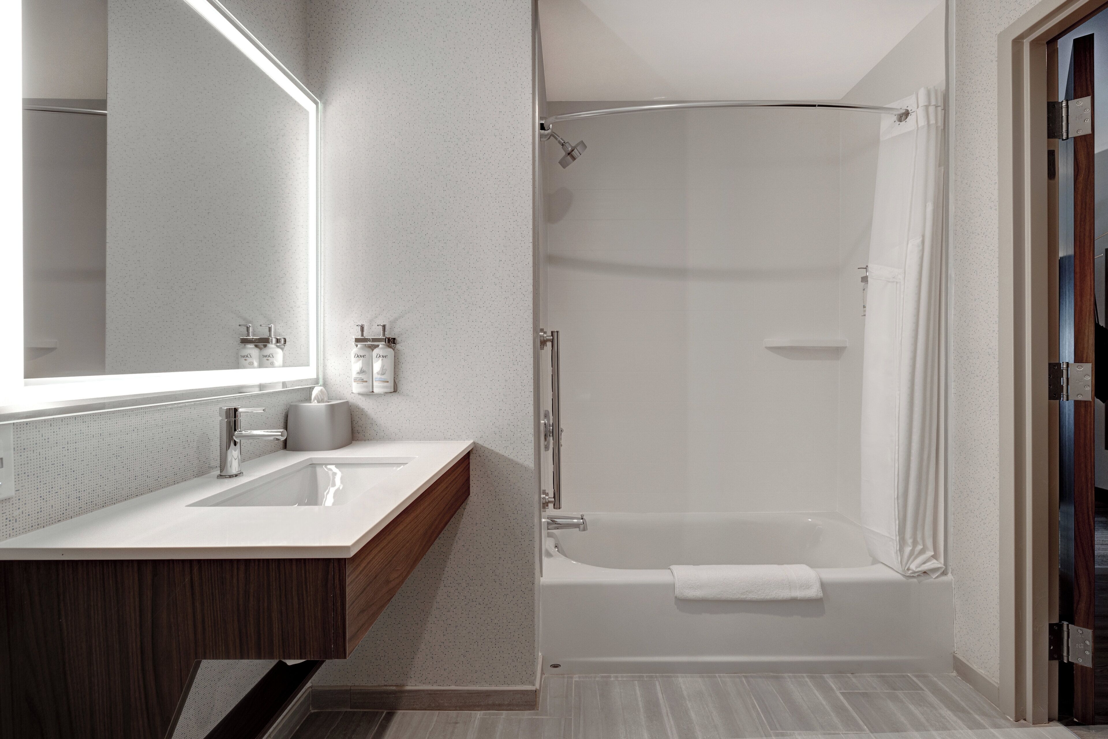 A modern bathroom with a large mirror, a sink, a shower, and a bathtub.