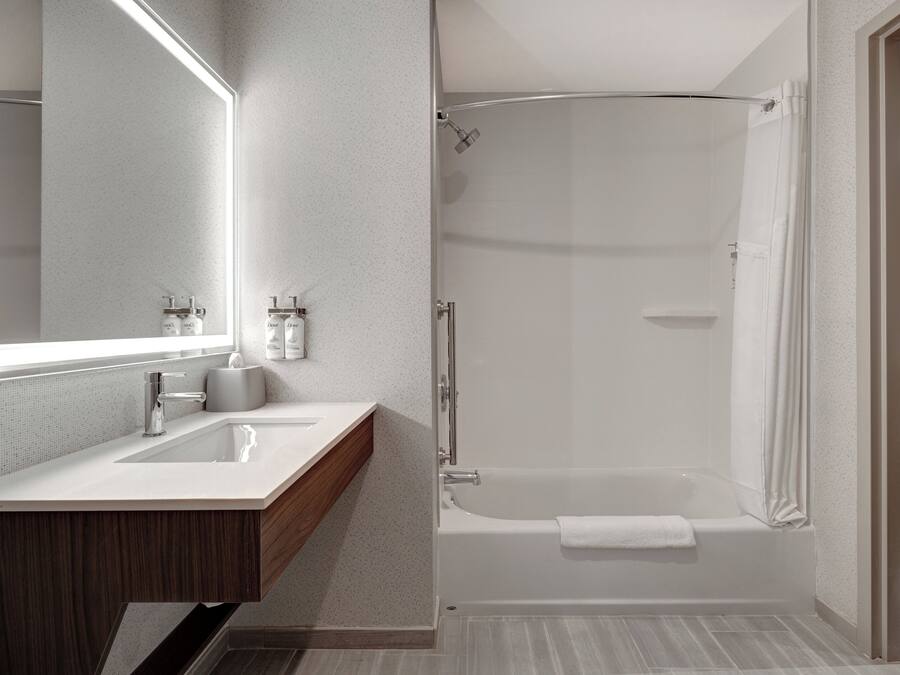 A modern bathroom with a large mirror, a sink, a shower, and a bathtub.