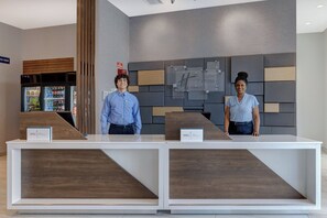 A reception desk with two staff members, a vending machine, and a Holiday Inn Express sign on the wall. - Holiday Inn Express & Suites Glendale Downtown by IHG (Glendale)