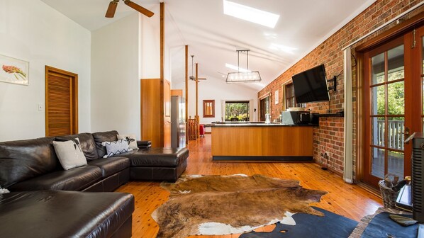 Ein modernes Wohnzimmer mit Ledersofa, Couchtisch aus Holz und einem großen Fellteppich.
