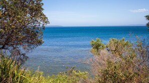 Un paysage côtier avec une mer bleue et limpide, de la végétation et des reliefs terrestres visibles au loin.