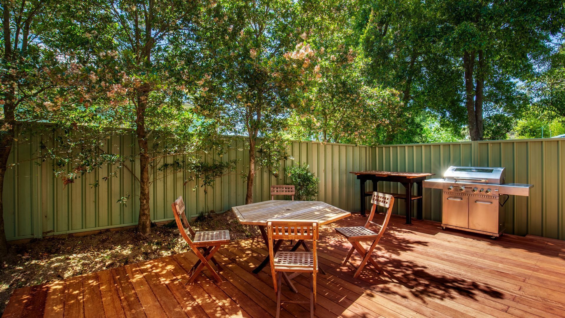A wooden deck with a grill and two chairs.