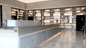 Un comptoir d’accueil moderne au design épuré, entouré d’étagères remplies de livres et de supports promotionnels.