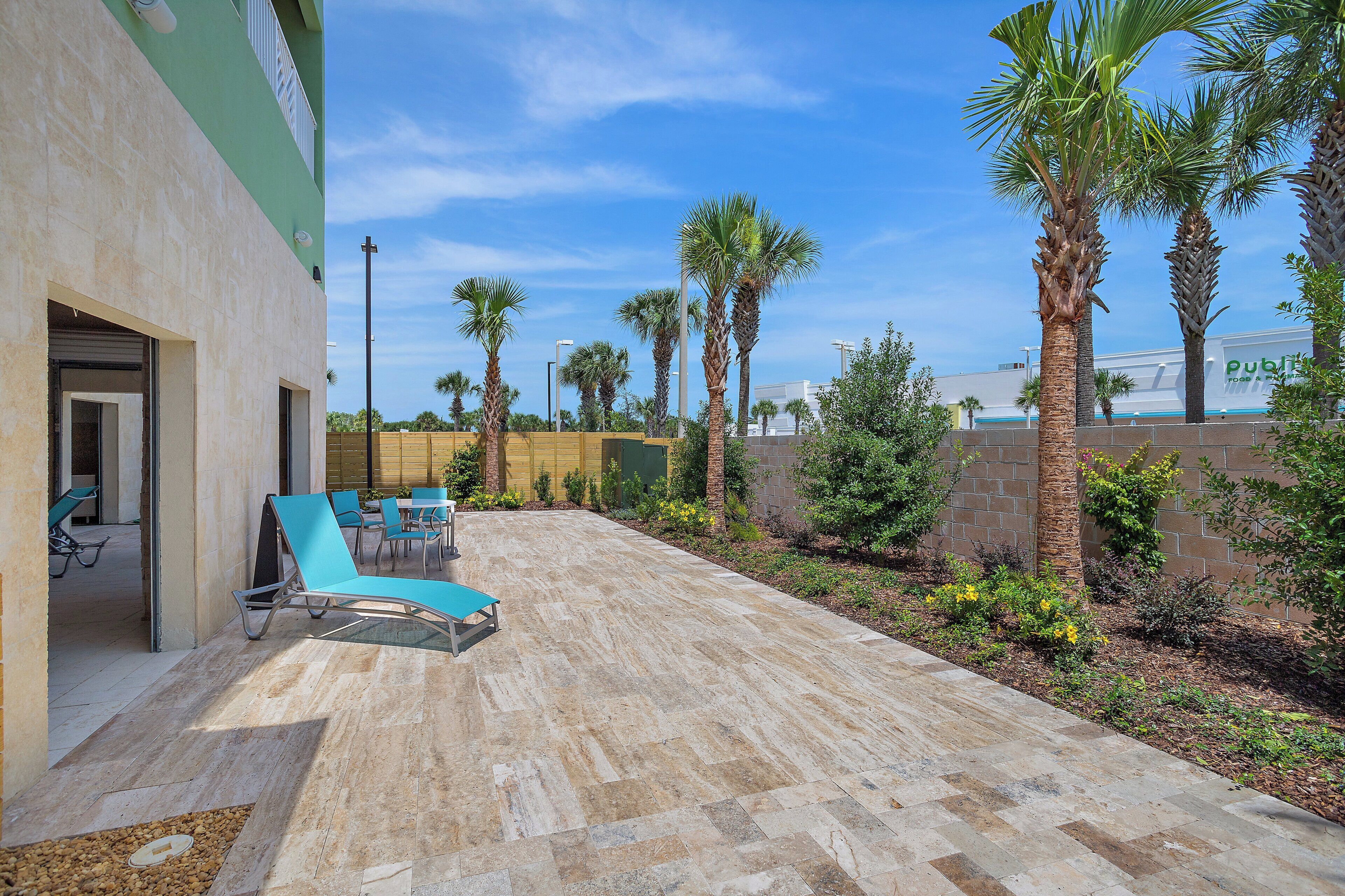 A patio area with outdoor seating, palm trees, and a building with a 'public' sign.
