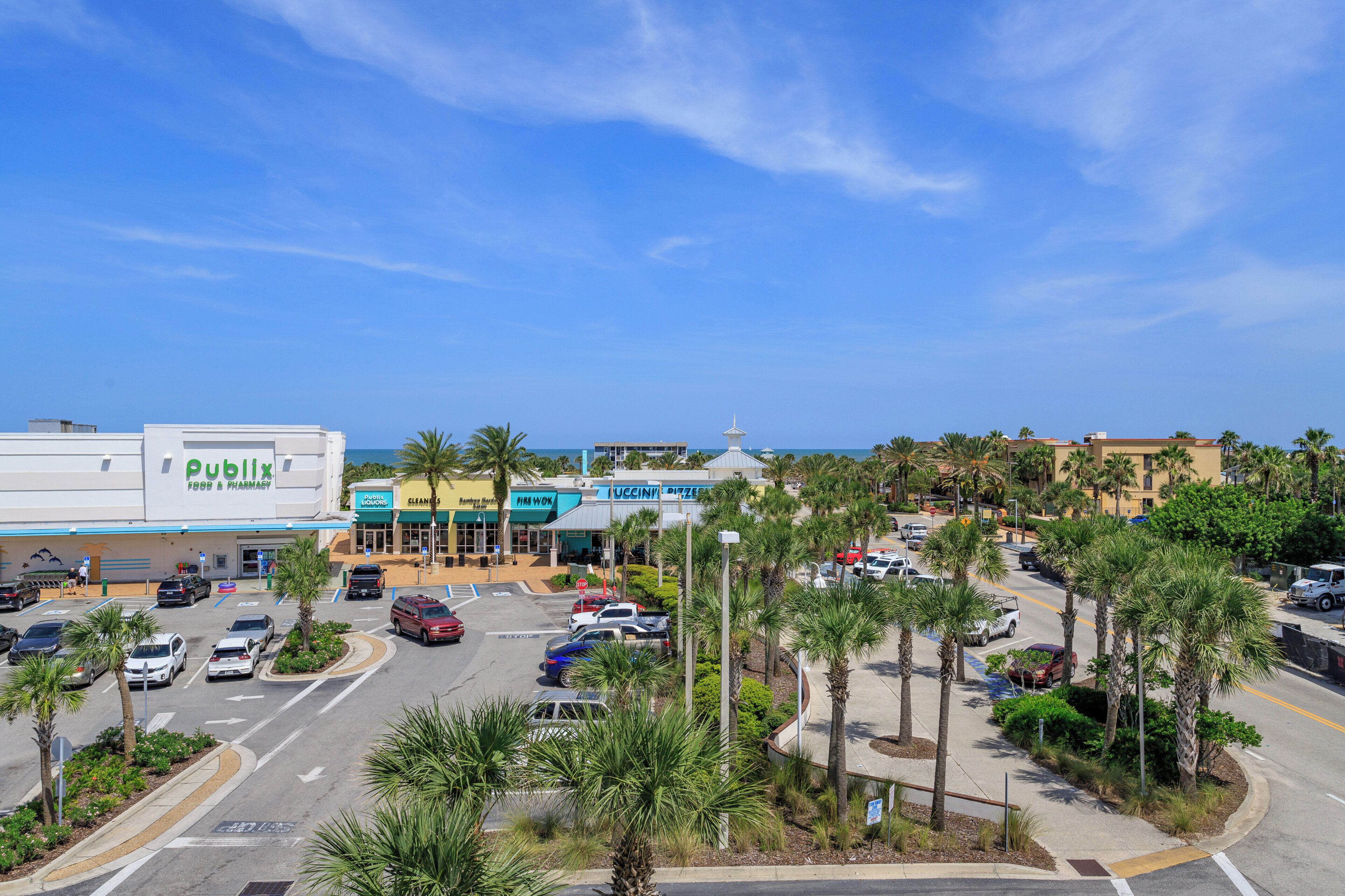 A parking lot with multiple cars, a pharmacy, and a food court with various eateries.