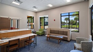 A modern hotel lobby with a reception desk, seating area, and large windows offering views of palm trees. - Holiday Inn Express St. Augustine - Vilano Beach by IHG (St. Augustine)