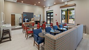 A modern cafe with seating areas, a coffee station, and a view of the outdoors. - Holiday Inn Express St. Augustine - Vilano Beach by IHG (St. Augustine)
