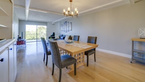 A spacious dining area with a wooden table and chairs, a chandelier, and a view of the outdoors.