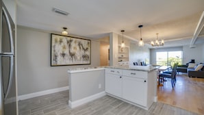 A modern kitchen with white cabinetry, a marble countertop, and pendant lighting.