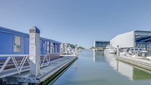 A marina with a blue building labeled "MAXIMO MARINA PRIVATE CLUB," a covered boat dock, and a large white building with a glass facade.