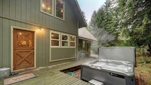 Ett hus med en bubbelpool på bakgården, ett trädäck och en garageport.