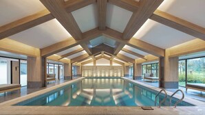 En stor indendørs swimmingpool med træbjælker og siddepladser.