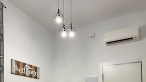 A room with a beige sofa, a wall-mounted air conditioner, a door, and a 'welcome' sign.