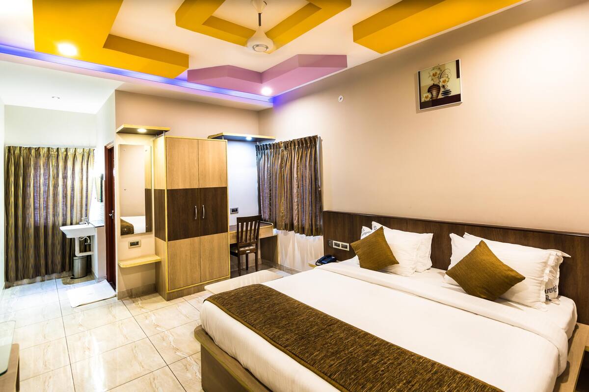 Una habitación de hotel con cama, mesita de noche, lámpara y armario.