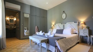 Ein Schlafzimmer mit einem Bett, Nachttischen, einer Bank und einem Spiegel.