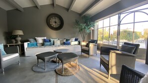 Ein modernes Wohnzimmer mit großem Fenster, einer Sofagarnitur und einer Wanduhr.