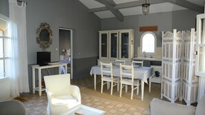 Ein Zimmer mit Esstisch, Stühlen, Fernseher und Schrank.