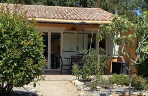 Una casa con tetto in tegole, un portico coperto e un giardino con rocce e piante.
