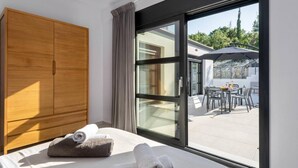 A hotel room with a bed, a wooden wardrobe, and a sliding glass door leading to an outdoor patio with a table and chairs. - Swedish-style Villa Salz (Unknown)