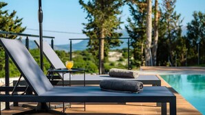 A poolside lounge with a view of a mountain and trees. - Swedish-style Villa Salz (Unknown)
