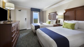 A hotel room with two beds, a television, a dresser, and a window with a view.