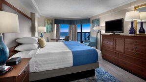 Une chambre d’hôtel avec un lit, une télévision, une commode et une vue sur l’océan.