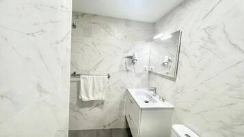 Un baño con pared de mármol, un lavabo, un inodoro y un perchero para toallas.