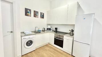 Cocina compacta equipada con lavadora, microondas y refrigerador.