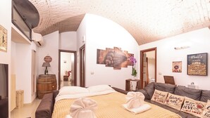 A hotel room with a bed, a sofa, and a dining table. There is a wall with a clock and a picture. - The wine cave _Stylish 110sqm Flat, Strong WiFi, AC, Milan Central Station (Milano)